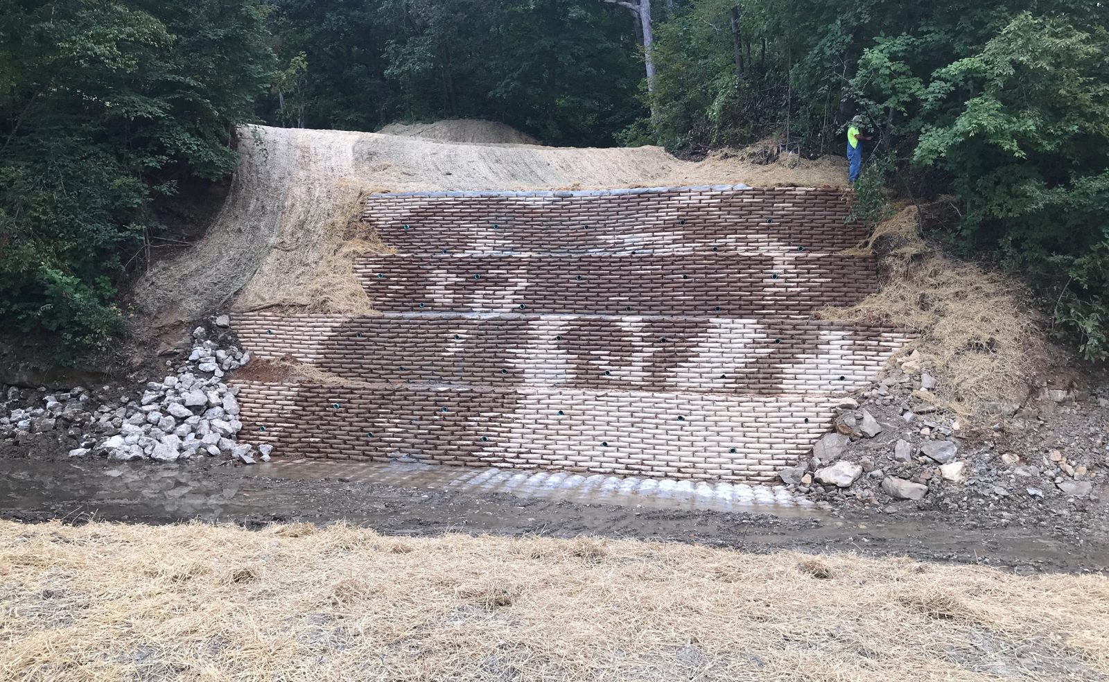 A creek bank rebuilt as a stepped wall over a pipeline